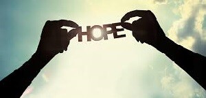 Picture of a person holding up the words "HOPE" to the sky