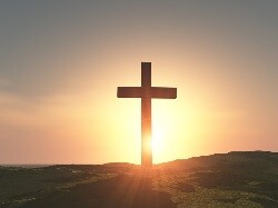 Picture of a cross in front of a sunset